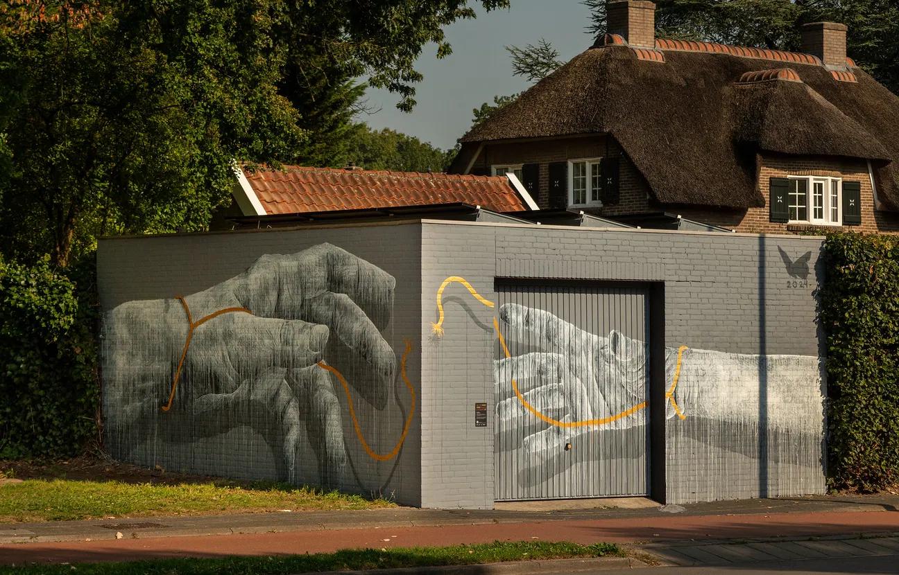 Muurschildering van twee handen die elkaar net niet raken met een gebroken touw ertussen