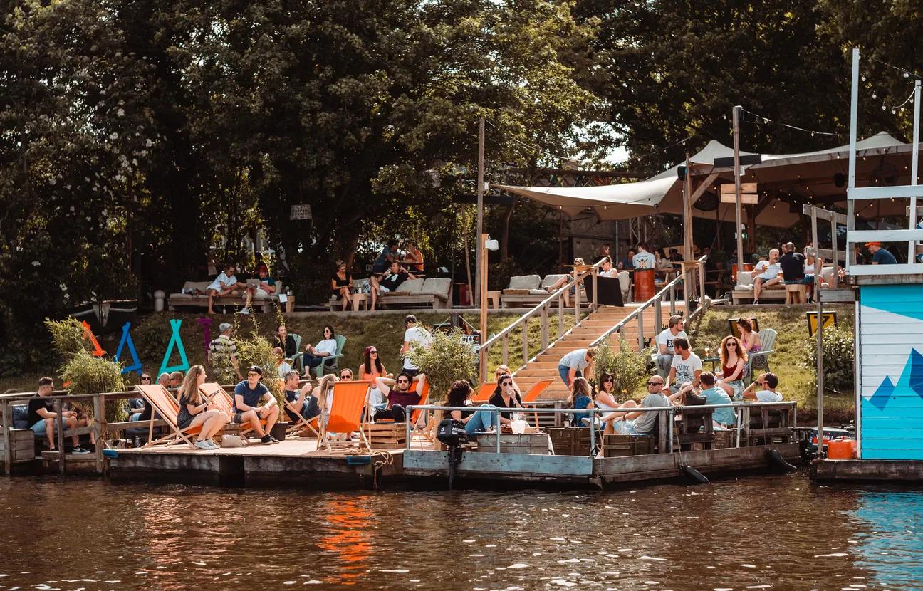 Terras vol met mensen aan het water.