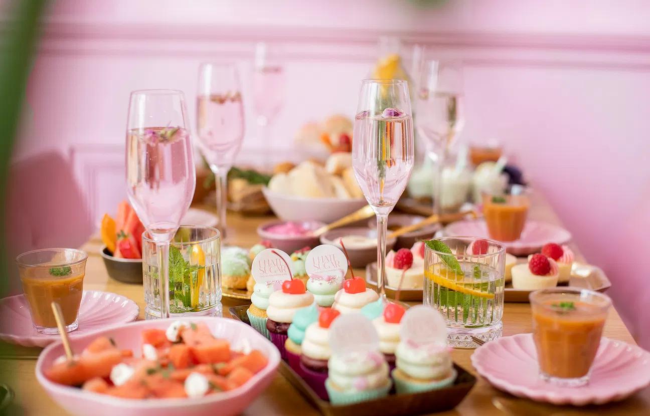 Feestelijk gedekte tafel met allerlei zoete en hartige lekkernijen in een roze decor.