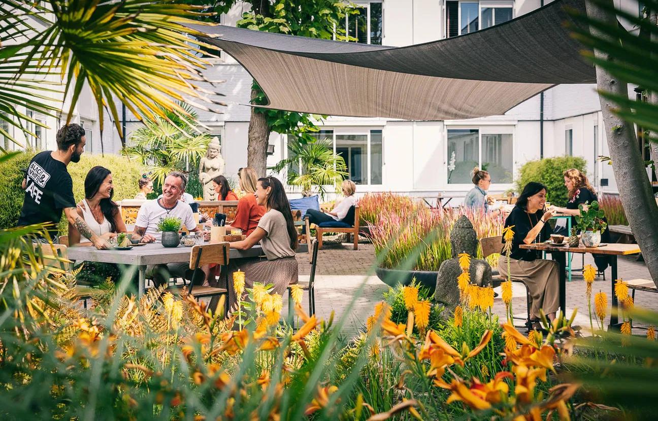 De tuin van Black & White Kafe met mensen op het terras